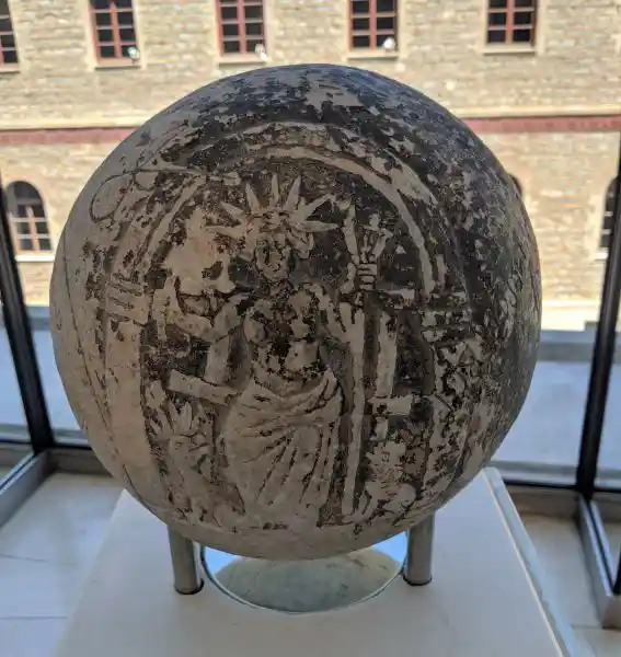 Depiction of Helios on a sphere, below an arch with a whip in one hand and three torches in the other.